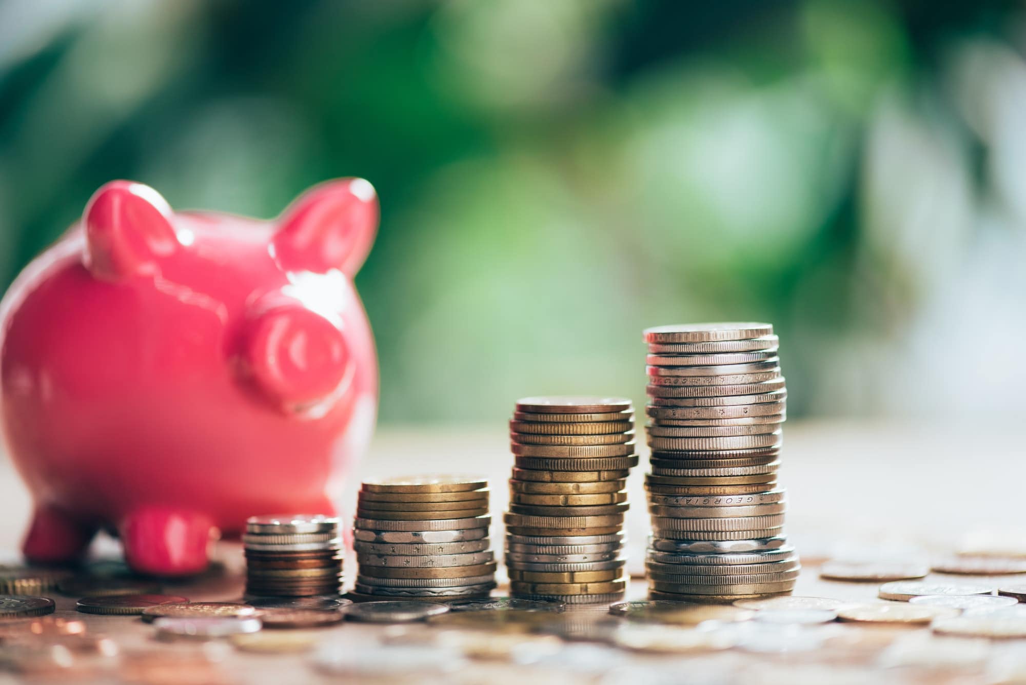 stacked coins and pink piggy bank close up view